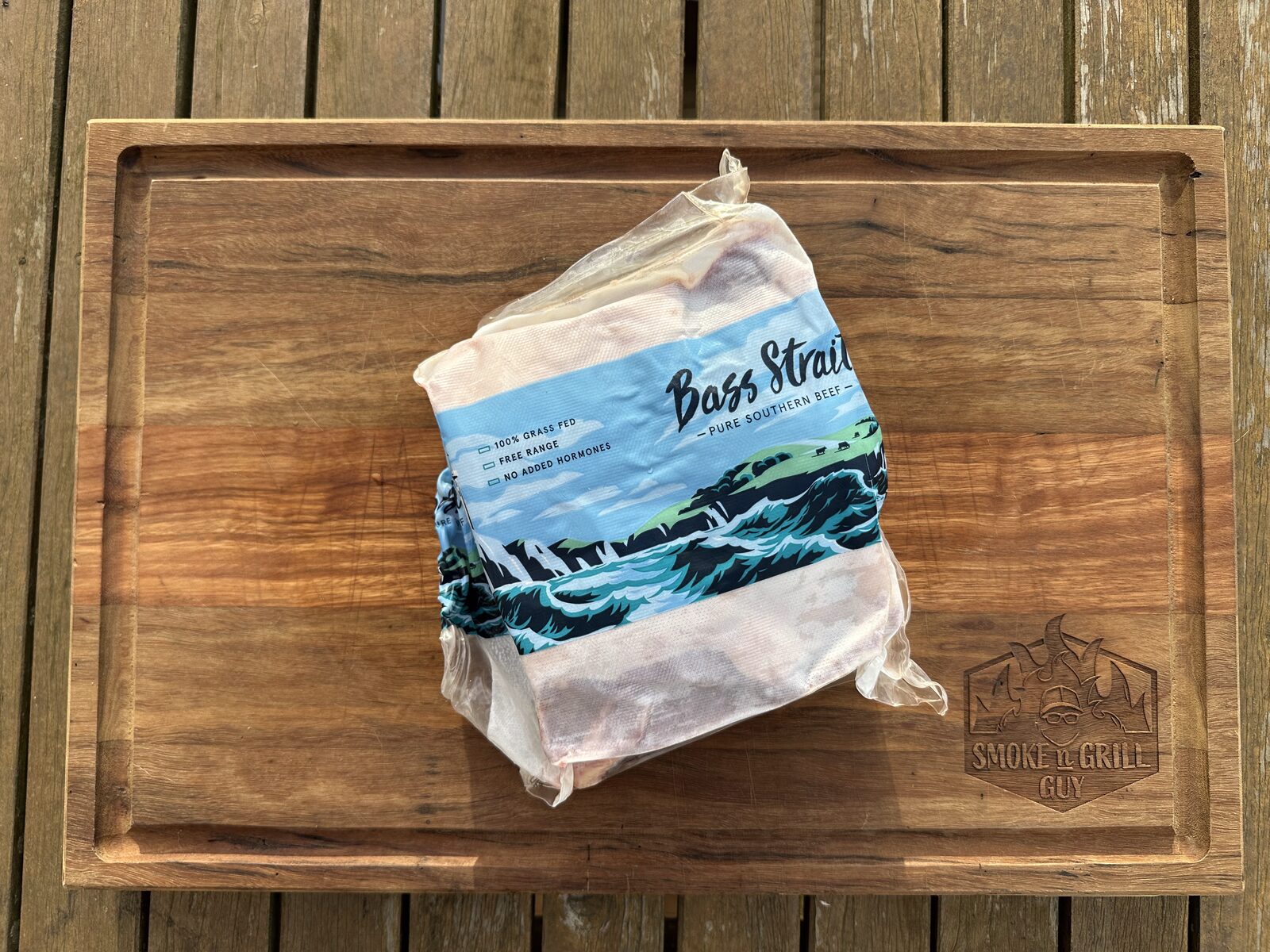 A vacuum-sealed pack of Bass Strait Beef short ribs on a wooden chopping board