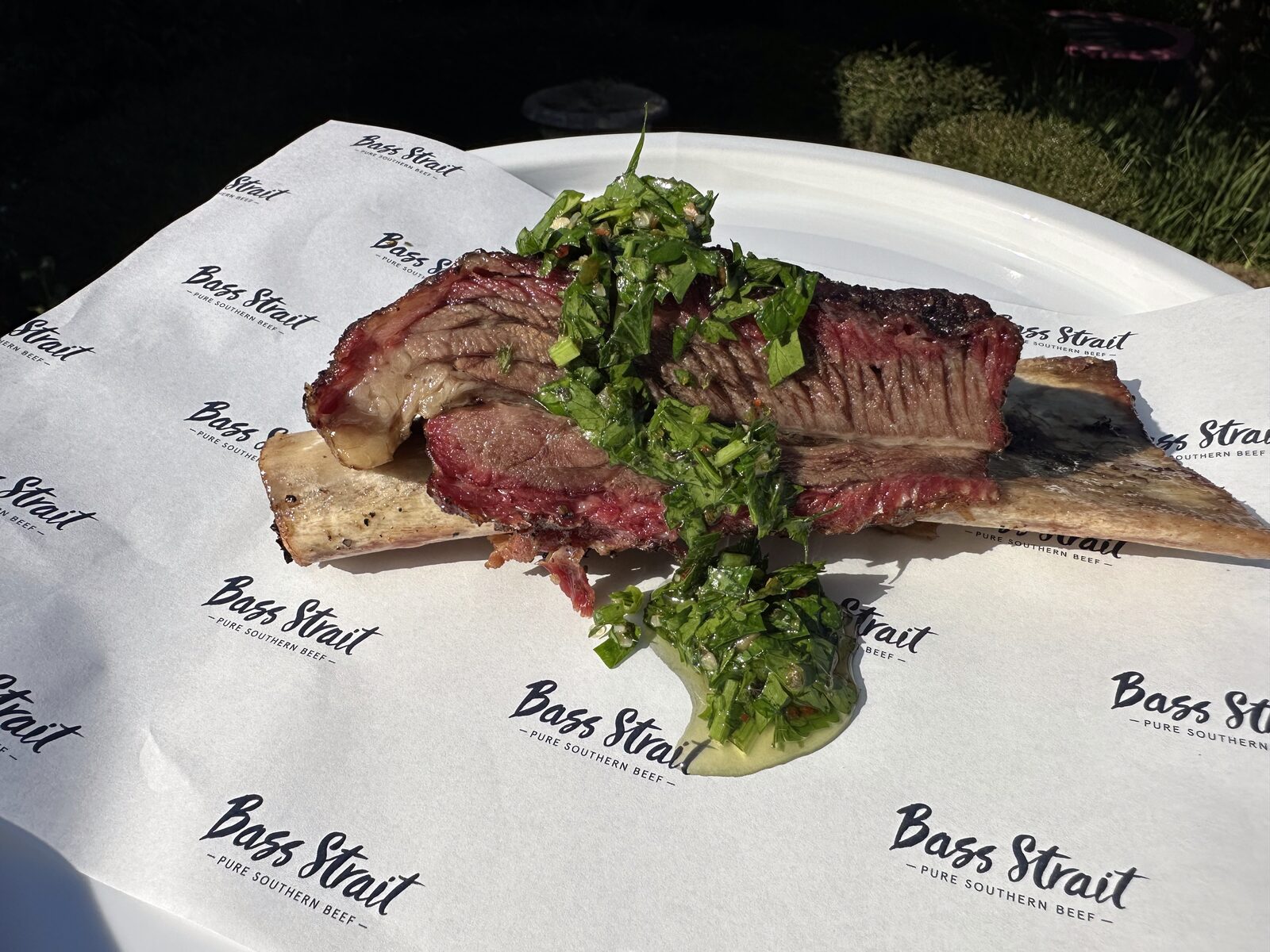 A smoked beef short rib on the bone plated with chimichurri on Bass Strait Beef paper