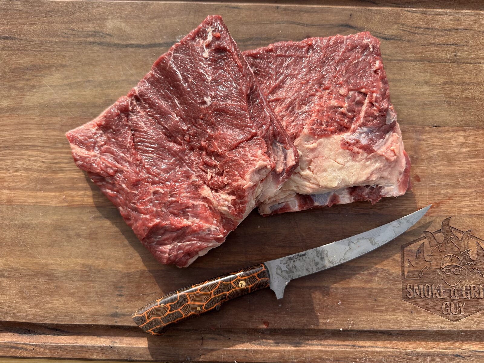 Two trimmed beef short rib slabs on a wooden board next to a boning knife