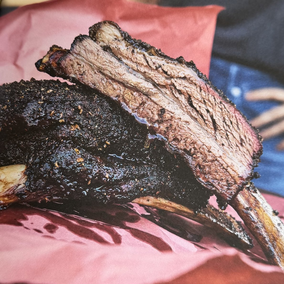 Sliced smoked beef plate ribs showing bark and smoke ring on pink butcher paper